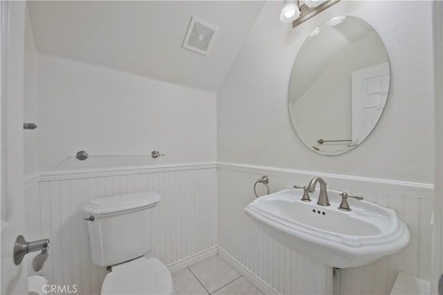 bathroom with wainscoting, toilet, tile patterned floors, and a sink