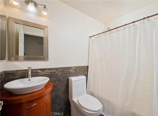 bathroom with toilet, a wainscoted wall, tile walls, vanity, and a shower with curtain