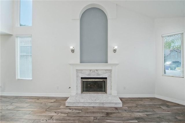 unfurnished living room with wood finished floors, a premium fireplace, and baseboards