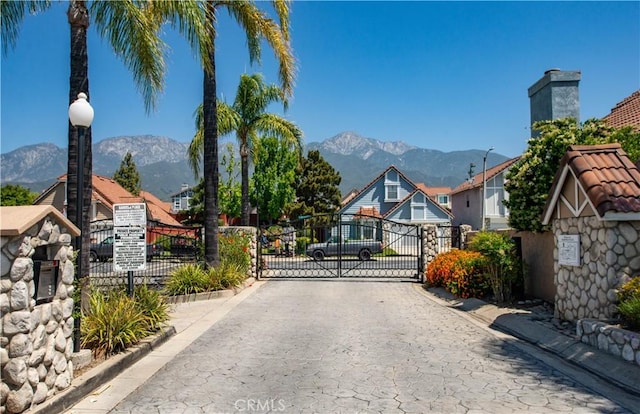 view of road with a gate, curbs, a mountain view, and a gated entry