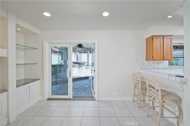 kitchen featuring recessed lighting, light tile patterned flooring, brown cabinets, a ceiling fan, and baseboards