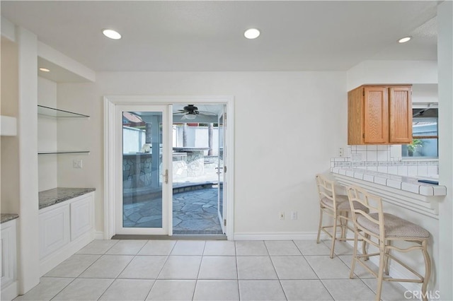 9788 Balaton St, Rancho Cucamonga, CA 91737 - kitchen featuring recessed lighting, light tile patterned floors, ceiling fan, brown cabinetry, and dark stone countertops