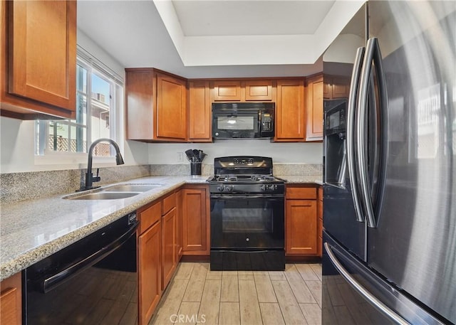 13722 Cerise Ave, Hawthorne, CA 90250 - kitchen featuring black appliances, a sink, light stone countertops, brown cabinetry, and light wood-style floors