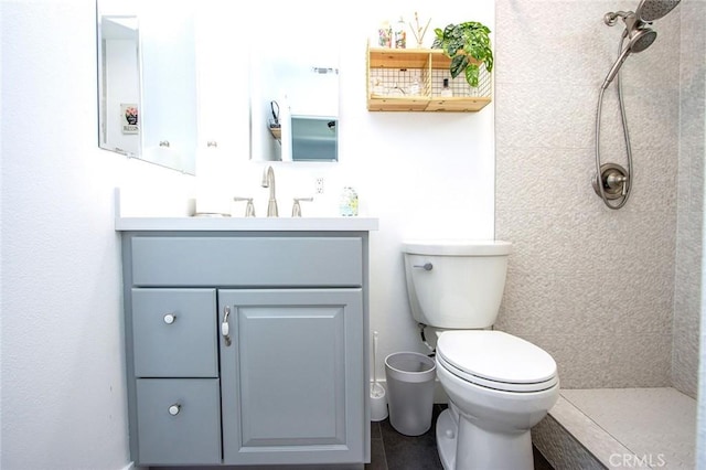 full bath with tiled shower, vanity, and toilet