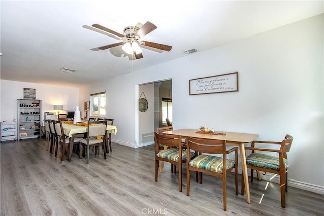 dining space featuring wood finished floors, baseboards, and a ceiling fan