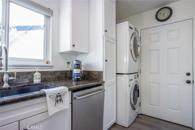 clothes washing area featuring stacked washing machine and dryer and wood finished floors