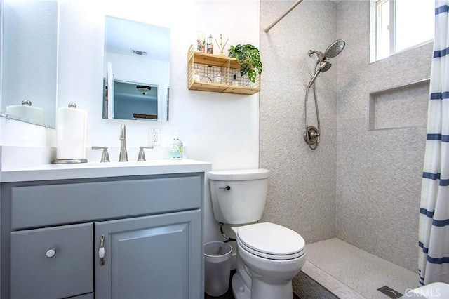 bathroom featuring tiled shower, toilet, and vanity