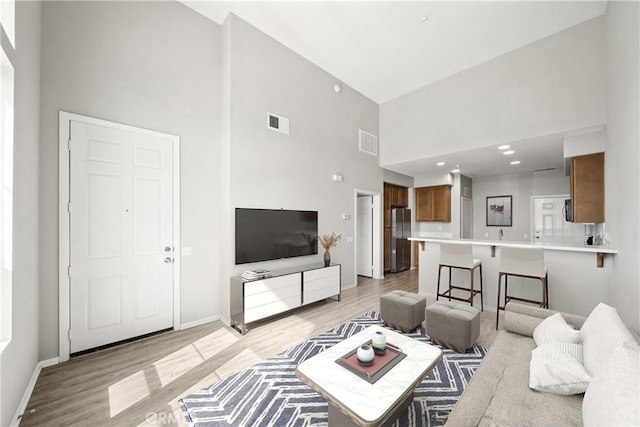 986 Coriander Dr Unit 304, Hemet, CA 92545 - living room featuring a towering ceiling, light wood-style floors, and baseboards
