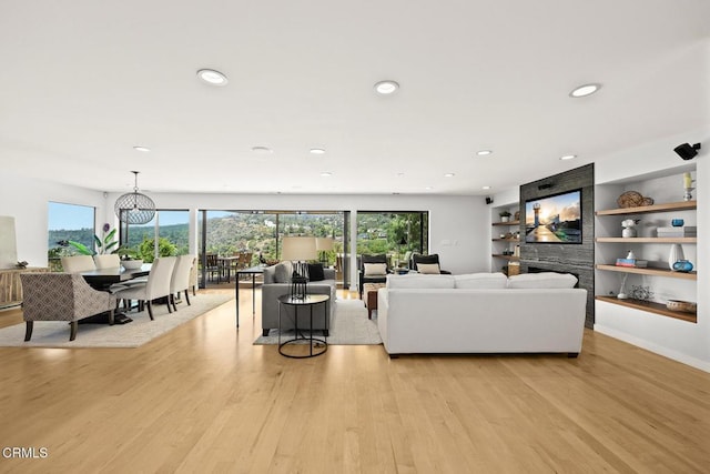 living area with healthy amount of natural light, light wood-style flooring, recessed lighting, built in shelves, and a fireplace