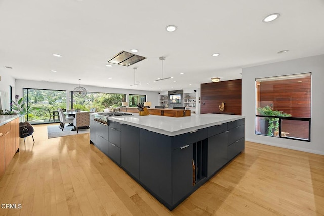 kitchen with modern cabinets, recessed lighting, light countertops, a large island, and light wood finished floors