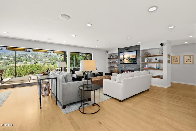 living area featuring light wood-style flooring, recessed lighting, baseboards, and a fireplace