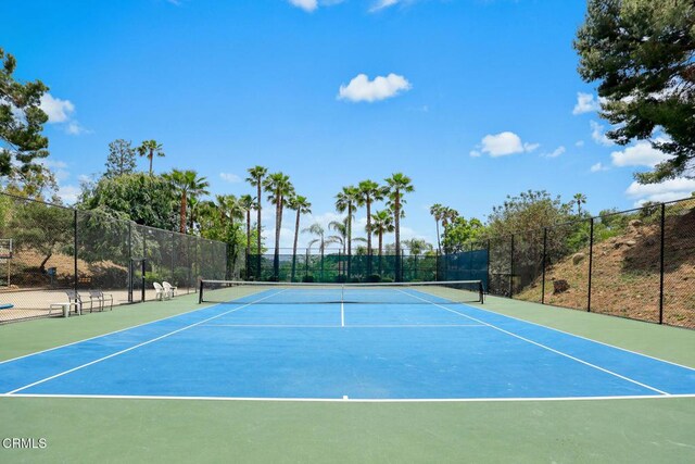view of tennis court featuring community basketball court and fence