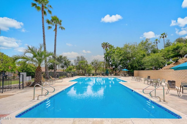 community pool with fence and a patio area