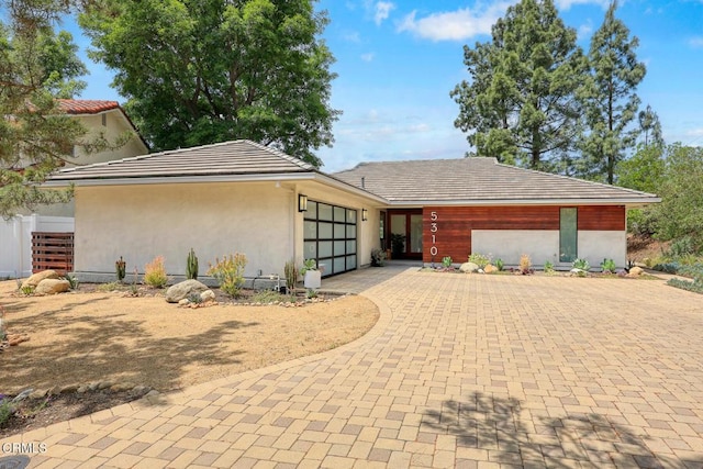 view of front of house featuring decorative driveway, a garage, and stucco siding