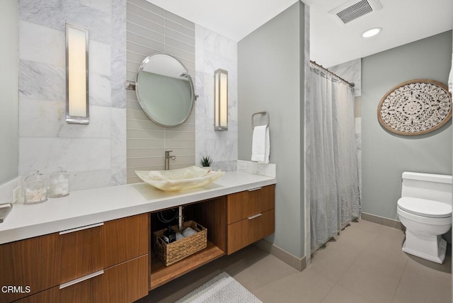 bathroom featuring toilet, vanity, tile patterned floors, baseboards, and decorative backsplash