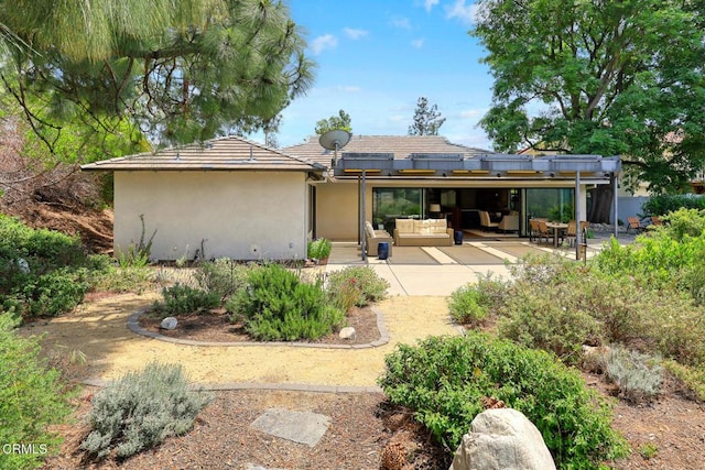 back of property with a patio area, outdoor lounge area, stucco siding, and a tiled roof