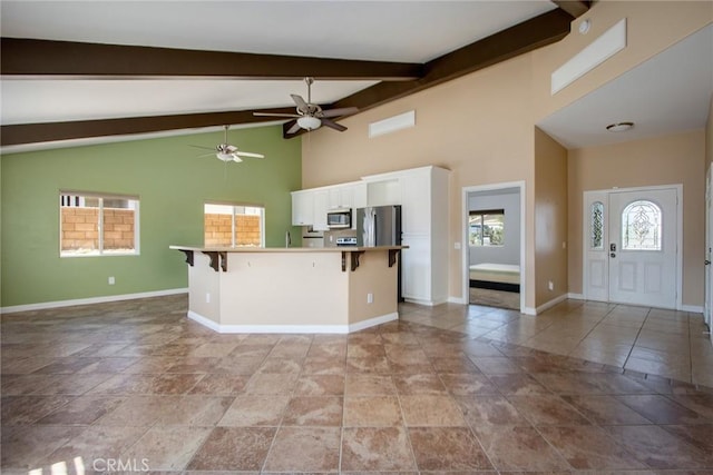 6649 Pine Spring Ave Unit 29, Palms, CA 92277 - kitchen with stainless steel appliances, white cabinets, a kitchen bar, a ceiling fan, and baseboards
