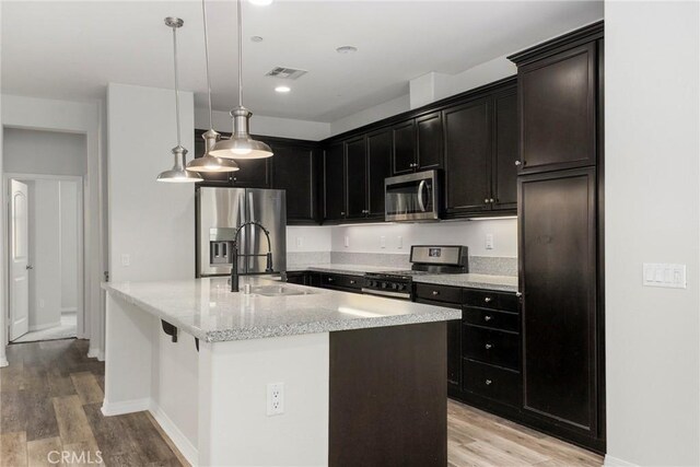 26703 Lexington Ln, Saugus, CA 91350 - kitchen with stainless steel appliances, a sink, light wood-type flooring, baseboards, and a kitchen island with sink