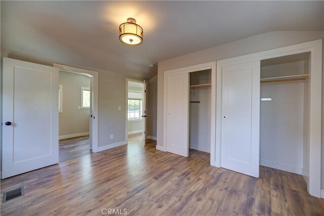 810 Meinecke Ave, San Luis Obispo, CA 93405 - unfurnished bedroom featuring wood finished floors, two closets, and vaulted ceiling