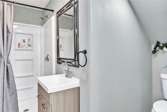 2517 Macbeth Ave, Corona, CA 92882 - bathroom featuring a textured wall, a stall shower, toilet, and vanity