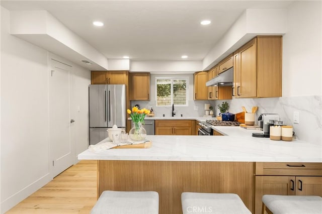 5662 Trail View Pl, Yorba Linda, CA 92886 - kitchen featuring appliances with stainless steel finishes, under cabinet range hood, a sink, a peninsula, and light wood-style floors