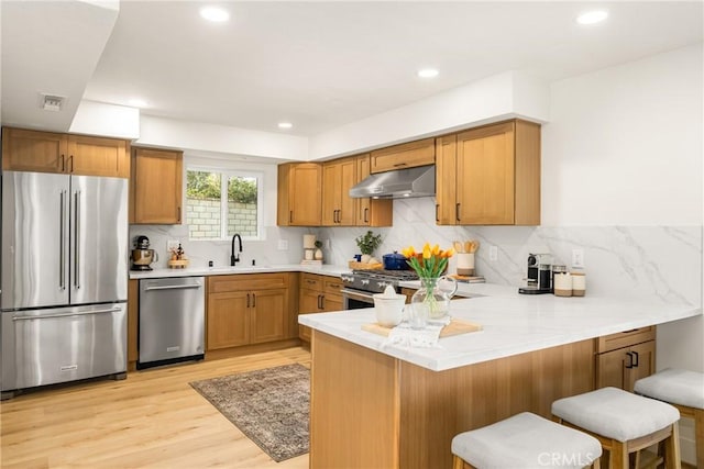5662 Trail View Pl, Yorba Linda, CA 92886 - kitchen with high quality appliances, under cabinet range hood, a peninsula, a sink, and light wood-style floors