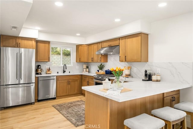 5662 Trail View Pl, Yorba Linda, CA 92886 - kitchen featuring high quality appliances, under cabinet range hood, a peninsula, light wood-style flooring, and a breakfast bar