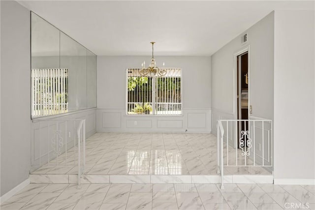 1403 W Westmont Dr, Anaheim, CA 92801 - unfurnished room with marble look tiles, a chandelier, a decorative wall, and wainscoting