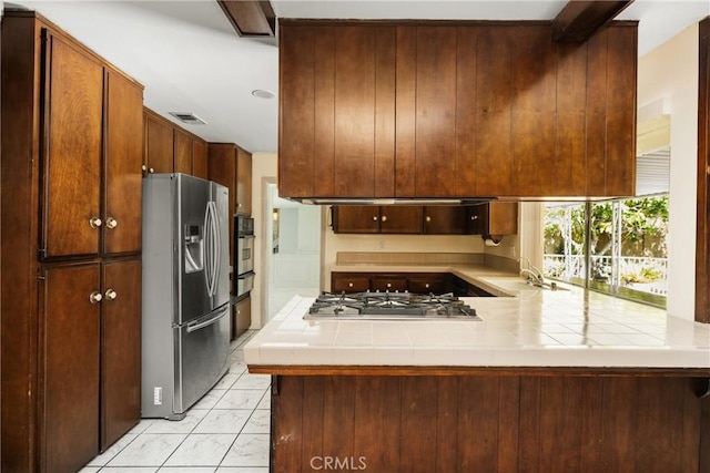 1403 W Westmont Dr, Anaheim, CA 92801 - kitchen featuring appliances with stainless steel finishes, tile countertops, light marble finish floors, a peninsula, and a warming drawer