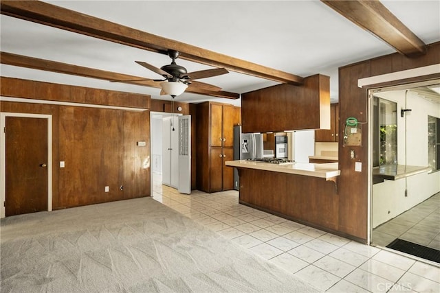 1403 W Westmont Dr, Anaheim, CA 92801 - kitchen with beamed ceiling, wooden walls, stainless steel appliances, a peninsula, and a ceiling fan