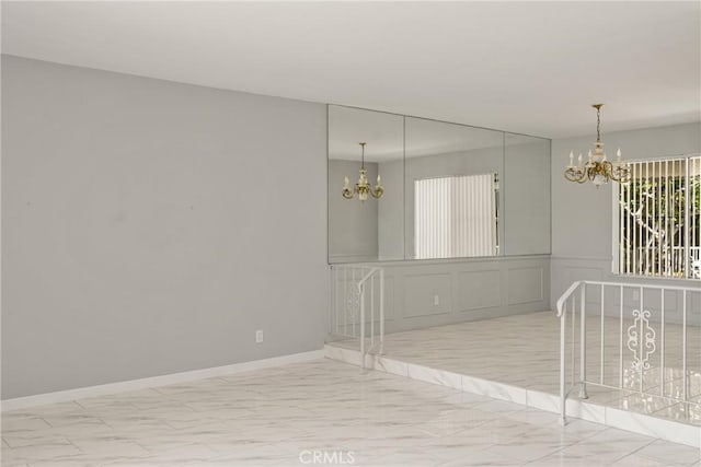 1403 W Westmont Dr, Anaheim, CA 92801 - unfurnished room with a chandelier, marble finish floors, baseboards, and a decorative wall
