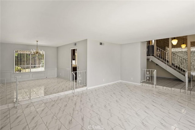 1403 W Westmont Dr, Anaheim, CA 92801 - unfurnished living room with a chandelier, marble look tile flooring, stairs, a wainscoted wall, and a decorative wall