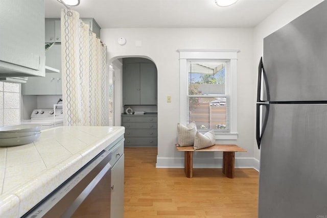 3536 Park Villa, San Diego, CA 92104 - kitchen with stainless steel appliances, tile countertops, light wood-style flooring, washing machine and dryer, and gray cabinetry
