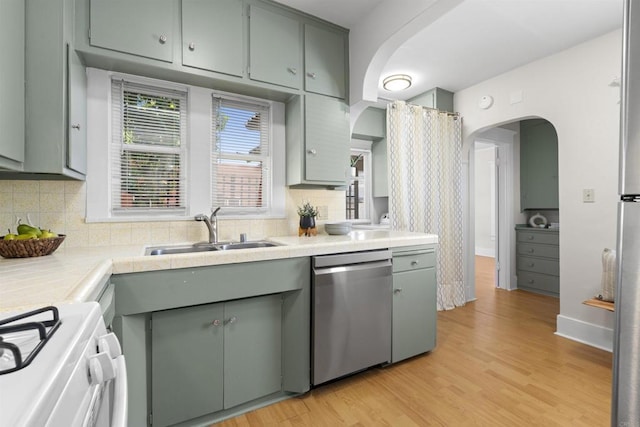 3536 Park Villa, San Diego, CA 92104 - kitchen with dishwasher, a sink, arched walkways, decorative backsplash, and light wood finished floors