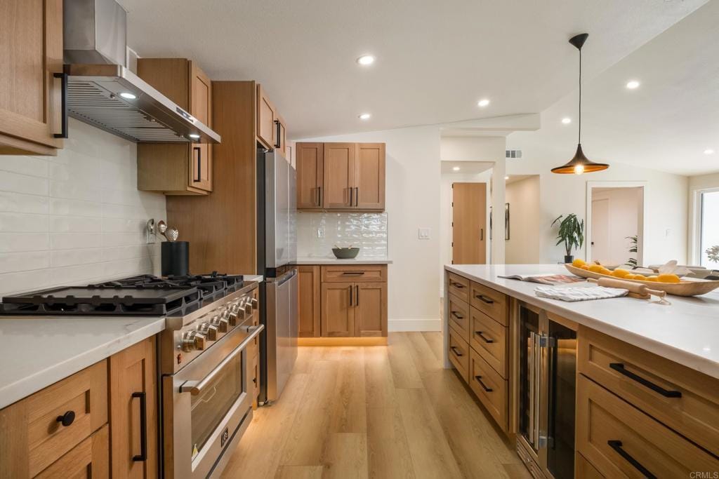 2434 Moonstone Dr, San Diego, CA 92123 - kitchen featuring appliances with stainless steel finishes, wall chimney exhaust hood, beverage cooler, light wood-style flooring, and light countertops