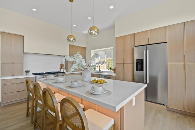 1736 Blackbird Cir, Carlsbad, CA 92011 - kitchen with appliances with stainless steel finishes, light countertops, a kitchen bar, light brown cabinetry, and recessed lighting