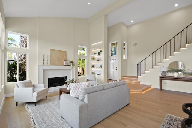 1736 Blackbird Cir, Carlsbad, CA 92011 - living room with high vaulted ceiling, stairs, wood finished floors, a fireplace, and baseboards