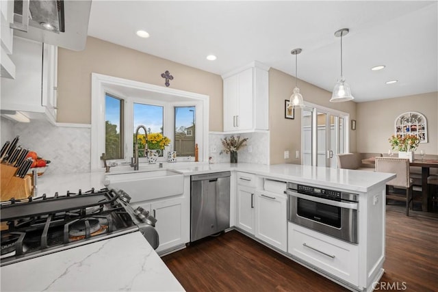 9 Northgrove Unit 11, Irvine, CA 92604 - kitchen with stainless steel appliances, a sink, a peninsula, backsplash, and light stone countertops