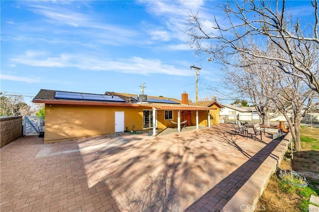 5306 W W Ave M4, Lancaster, CA 93536 - rear view of house with a patio area, stucco siding, a fenced backyard, solar panels, and a chimney