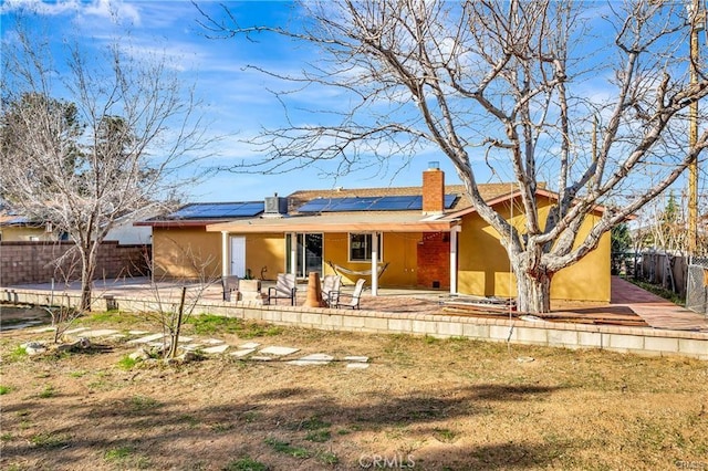 5306 W W Ave M4, Lancaster, CA 93536 - view of front facade featuring a chimney, a fenced backyard, solar panels, a patio area, and stucco siding