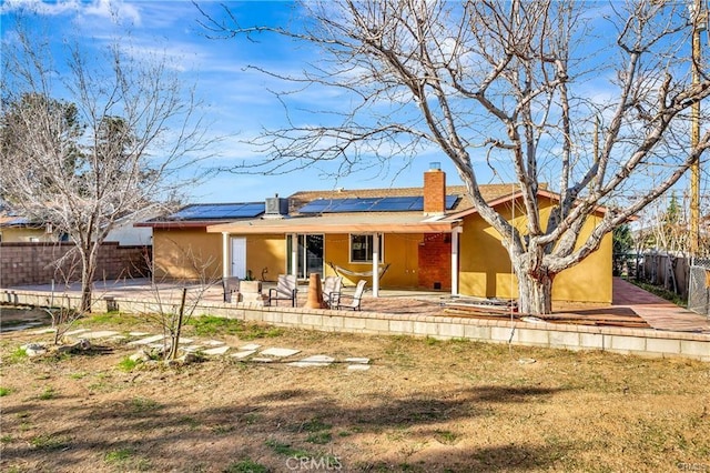 5306 W W Ave M4, Lancaster, CA 93536 - view of front of home with a chimney, a fenced backyard, roof mounted solar panels, a patio, and stucco siding