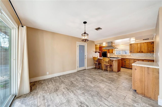 5306 W W Ave M4, Lancaster, CA 93536 - kitchen with brown cabinetry, wall chimney exhaust hood, light countertops, oven, and a peninsula