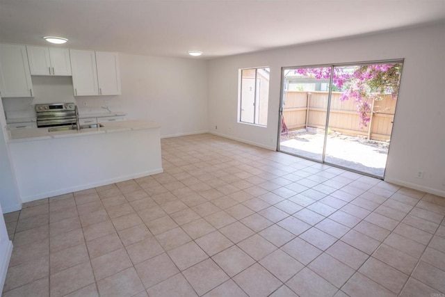 6860 Panamint Row Unit 2, San Diego, CA 92139 - kitchen featuring stainless steel electric range oven, light countertops, a sink, white cabinets, and baseboards