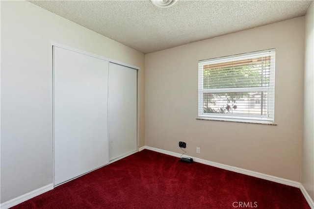 14889 Hartford Ln, Helendale, CA 92342 - unfurnished bedroom featuring dark colored carpet, a closet, baseboards, and a textured ceiling