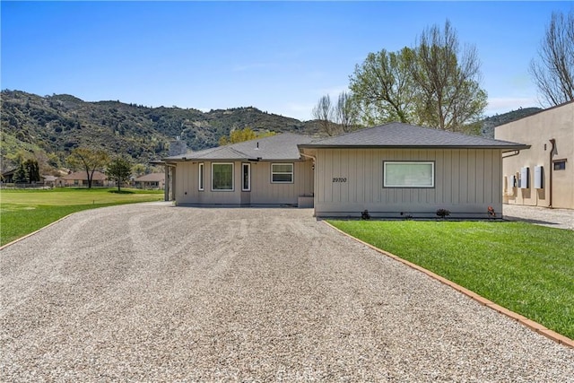 view of front of property with gravel driveway, a mountain view, and a front yard