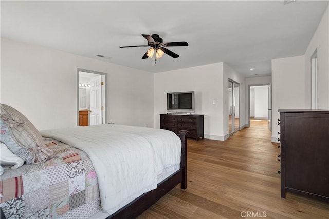 bedroom featuring wood finished floors, recessed lighting, baseboards, ceiling fan, and ensuite bath