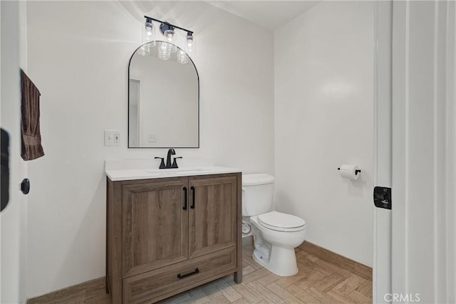 bathroom featuring toilet, vanity, and baseboards