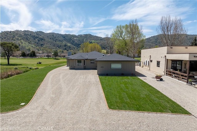 view of front facade featuring a mountain view, gravel driveway, and a front yard
