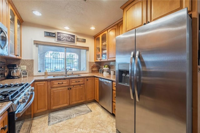 2219 S Elderberry Ave, Ontario, CA 91762 - kitchen featuring stainless steel appliances, a sink, a textured ceiling, light stone counters, and brown cabinetry