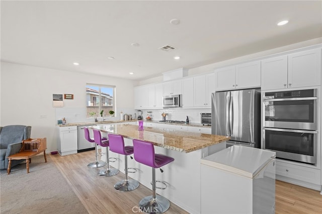27083 Comrade Cir, Menifee, CA 92585 - kitchen featuring stainless steel appliances, a center island, white cabinets, decorative backsplash, and recessed lighting